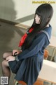A woman in a school uniform sitting on a chair.