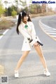 A woman in a white coat holding a gun on a road.