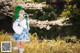 A woman with green hair standing in a field of flowers.