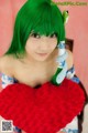 A woman with green hair holding a red heart.