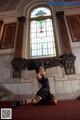 A woman sitting on the floor in front of a stained glass window.