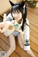 A woman in a sailor outfit sitting on a wooden deck.