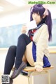 A girl in a school uniform sitting on a desk.