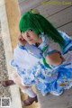 A woman with green hair sitting on a wooden bench.