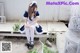A woman in a maid outfit sitting on a chair.