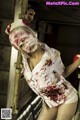 A woman dressed as a nurse with blood on her face.