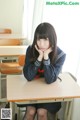 A young woman sitting at a desk in a classroom.