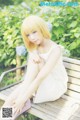 A woman sitting on a bench in a white dress.