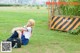 A woman sitting on the grass in front of a fence.