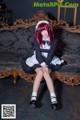 A woman in a maid outfit sitting on a couch.