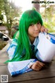 A woman with long green hair laying on a wooden table.