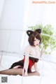 A woman in a cat costume sitting on a bed.
