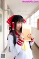 A woman in a school uniform holding a book.