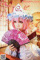 A woman with pink hair holding a pink fan.