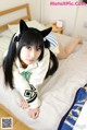 A woman in a cat costume laying on a bed.
