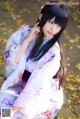 A woman in a kimono sitting on the ground.