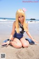 A woman in a sailor outfit sitting on the beach.