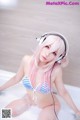 A woman in a bikini sitting in a bathtub with headphones on.