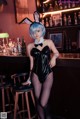 A woman in a bunny costume sitting at a bar.