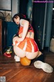 A woman in an orange and white cheerleader outfit crouching on a basketball.