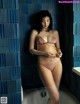 A pregnant woman standing in a bathtub in a bathroom.