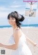 A woman in a white dress standing on a beach.