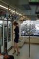 A woman in a blue dress standing on a subway train.