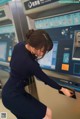 A woman in a blue dress is using an atm machine.