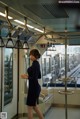 A woman in a black dress standing on a subway train.