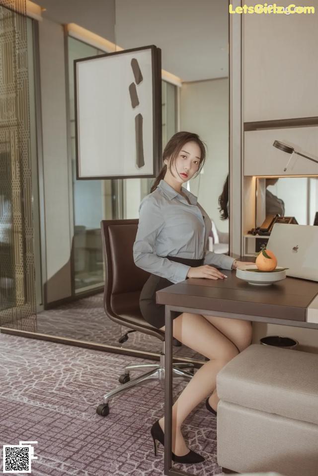 A woman sitting at a desk with a laptop computer.