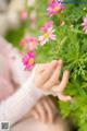 A woman holding a bunch of pink flowers in her hands.