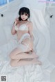 A woman in a white lingerie sitting on a bed.