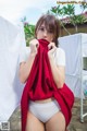 A woman in a white shirt and white panties holding a red towel.