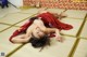 A woman in a red kimono laying on a tatami mat.