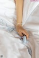 A woman's hand holding a computer mouse in bed.