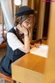 A woman sitting at a table with a book and a hat.