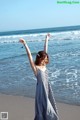 A woman standing on a beach with her arms outstretched.