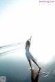 A woman in a white dress standing on a beach.