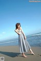 A woman standing on a beach next to the ocean.