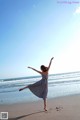 A woman standing on a beach with her arms outstretched.