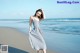 A woman standing on a beach next to the ocean.