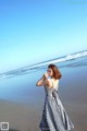 A woman standing on a beach next to the ocean.