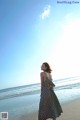 A woman standing on a beach next to the ocean.