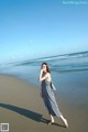 A woman walking on the beach talking on a cell phone.