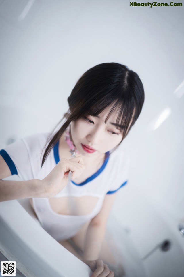 A woman sitting in a bathtub with her hand on her chin.