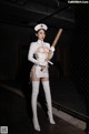 A woman dressed as a nurse holding a baseball bat.