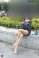 A woman sitting on a wall looking at her phone.