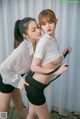 two asian women in white shirts and black shorts posing for the camera