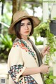 A woman wearing a straw hat holding a plant.