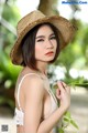 A woman in a straw hat holding a plant.